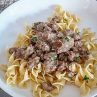 A plate of 30-minute beef stroganoff on noodles with parsley garnish.
