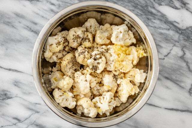 Air fryer cauliflower preparation: combining the florets with seasonings.