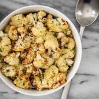 A bowl of air fryer roasted cauliflower ready to eat with parsley garnish.