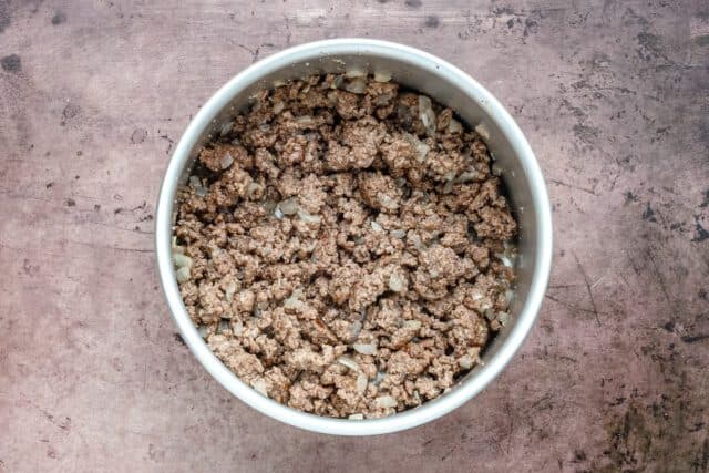 Crumbled cooked ground beef in a white bowl.