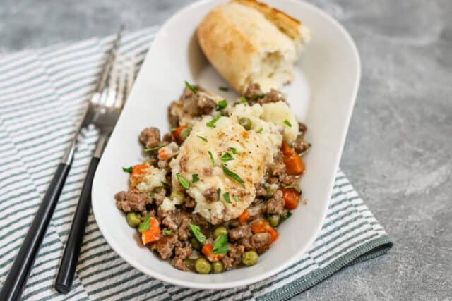 Creamy beef pot pie served with bread on a white platter.