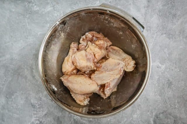 Air fryer chicken wings in a bowl with Parmesan cheese and parsley garnish.