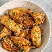 A serving bowl with air fryer garlic Parmesan chicken wings.