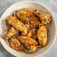 Crispy baked chicken wings garnished with chopped herbs and garlic crumbs.