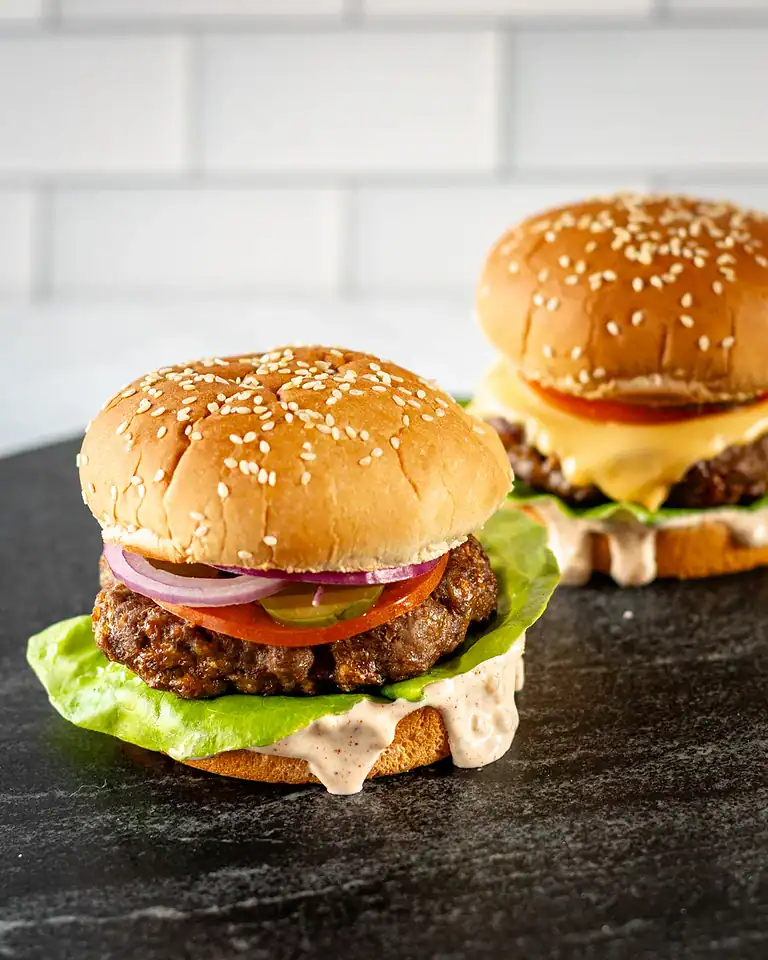 Juicy beef burgers with fresh vegetables and sesame seed buns.
