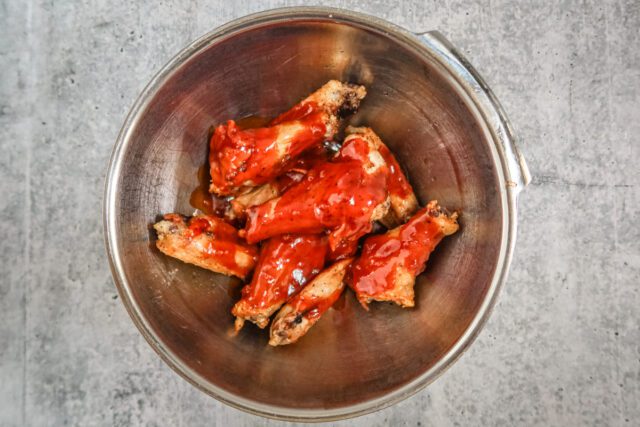 Tossing the chicken wings in the Korean BBQ sauce mixture.