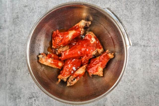 Succulent chicken wings coated in barbecue sauce in a metal bowl.