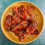 Tender glazed chicken wings with chopped herbs.