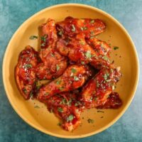 Tender glazed chicken wings with chopped herbs.
