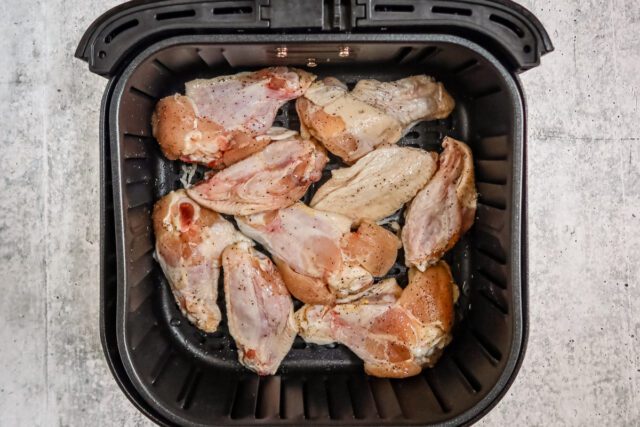 Chicken wings in the air fryer basket, ready to air-fry.
