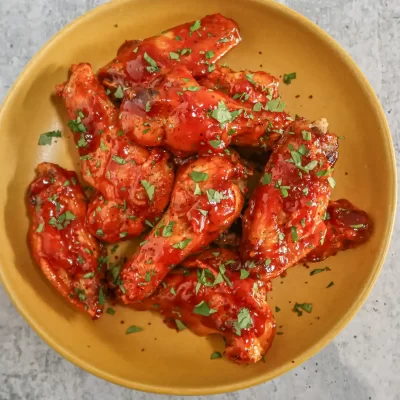Baked chicken wings glazed with spicy red sauce and chopped herbs.
