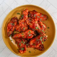 Air fryer Korean chicken wings in a serving bowl with garnish.
