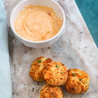 A plate of homemade air fryer potato croquettes made with leftover mashed potatoes, cheese, and herbs, and a dip on the side