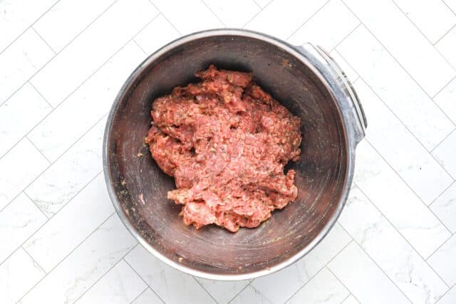 Ground beef mixture in a stainless steel bowl.