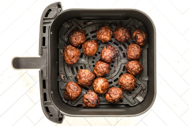 Shaped meatballs are in the air fryer basket.