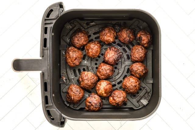 Golden-brown meatballs in an air fryer basket.