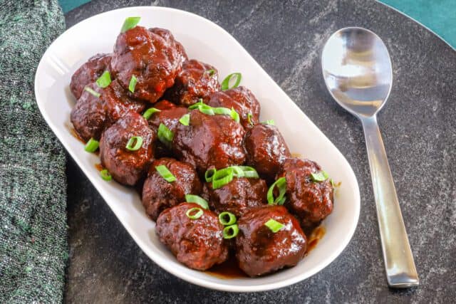 Tender meatballs coated in rich sauce and garnished with chopped green onions.