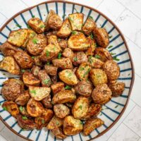 A serving plate with air fryer roasted potatoes garnished with parsley.