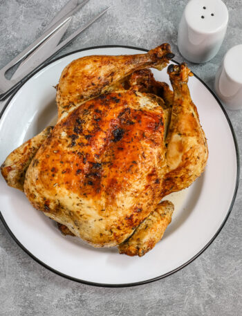 Air fryer whole roasted chicken on a plate, from Classic-Recipes.com.