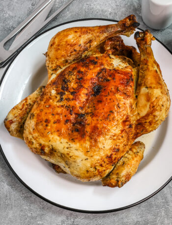 Whole air fryer roasted chicken on a plate.