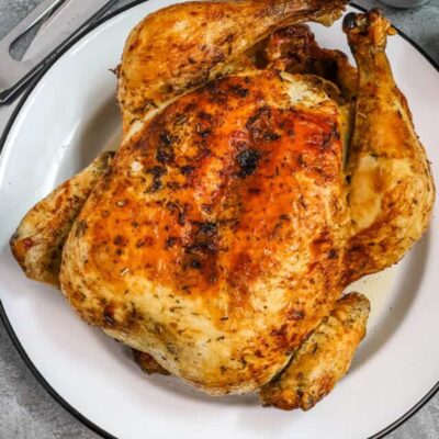Whole air fryer roasted chicken on a plate.