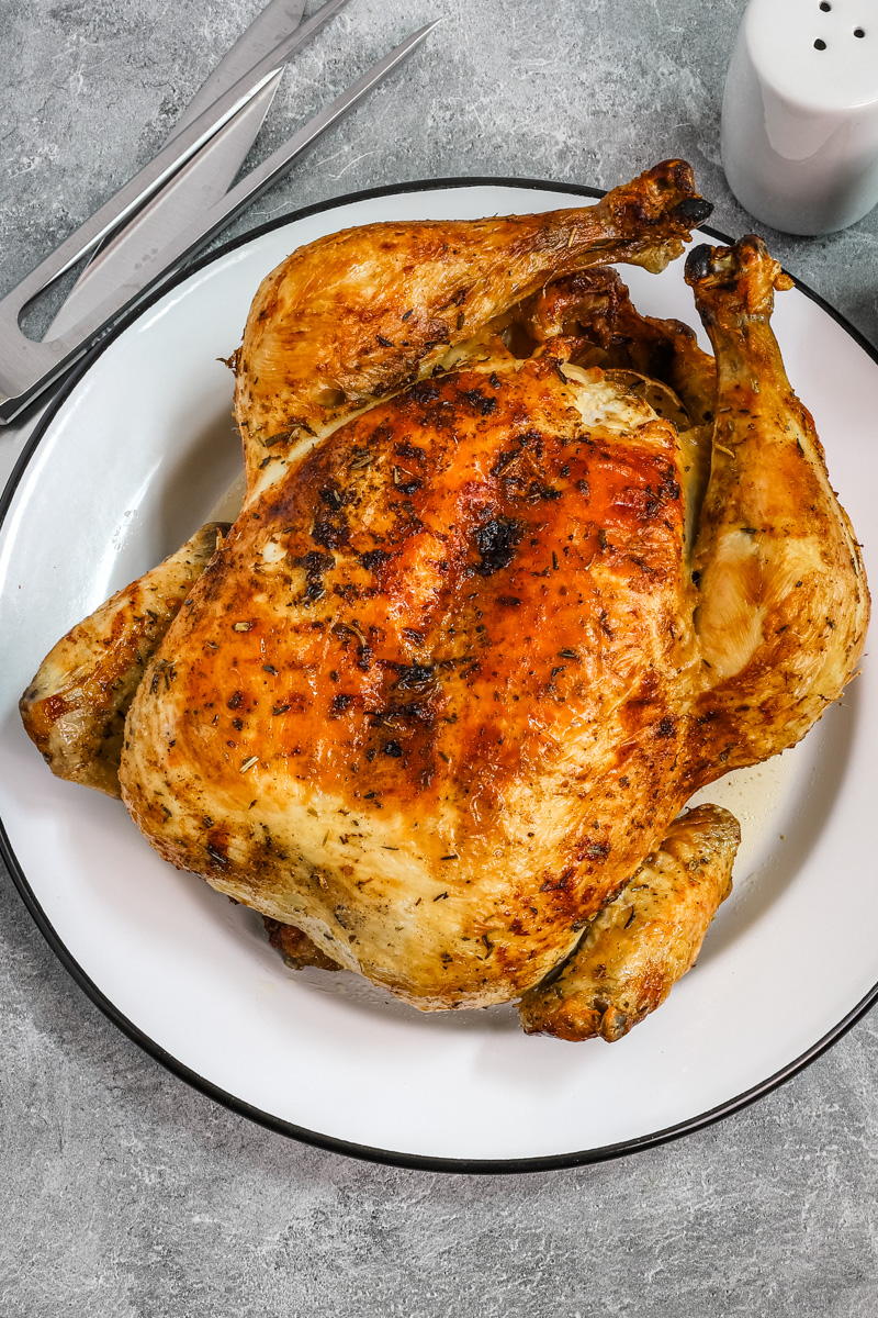 Whole air fryer roasted chicken on a plate.