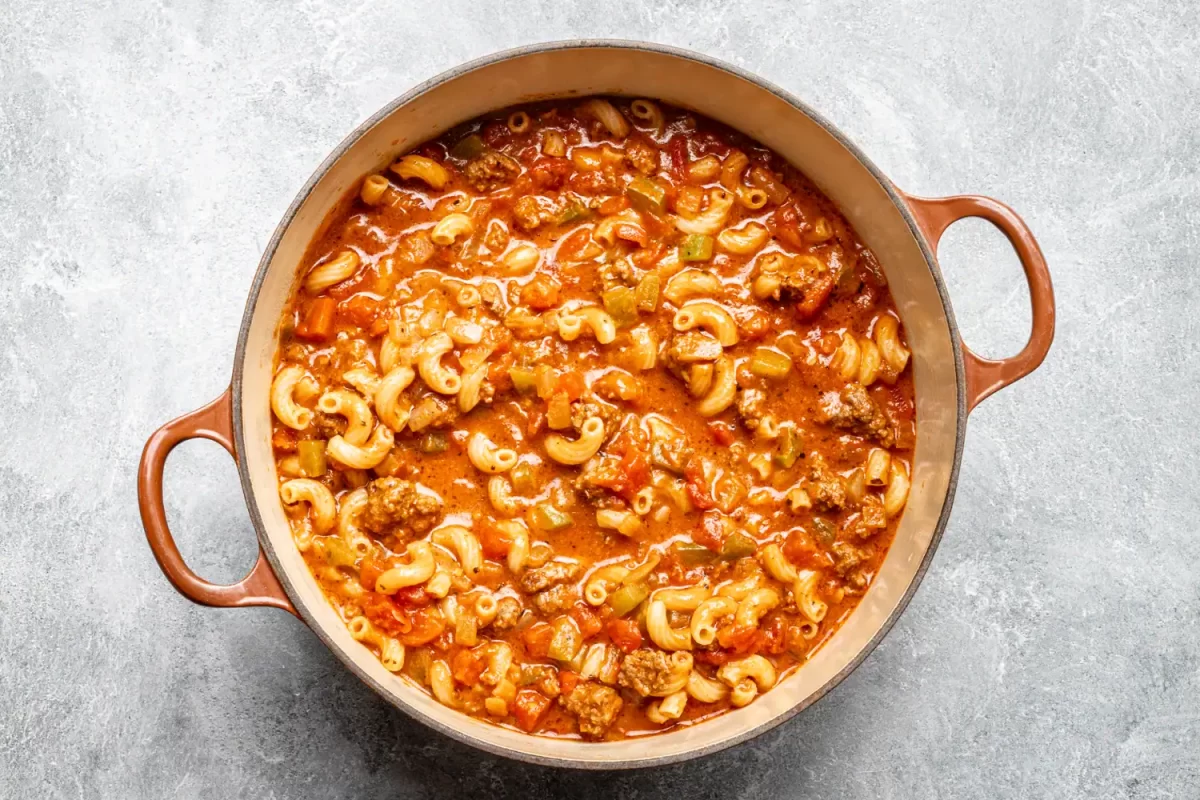 Ground beef and pasta casserole with tomato sauce in a round baking dish.