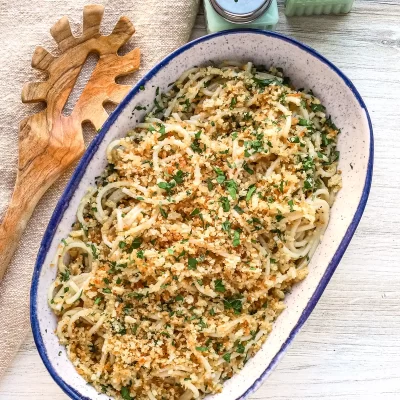 Golden breadcrumb-topped pasta dish garnished with herbs.