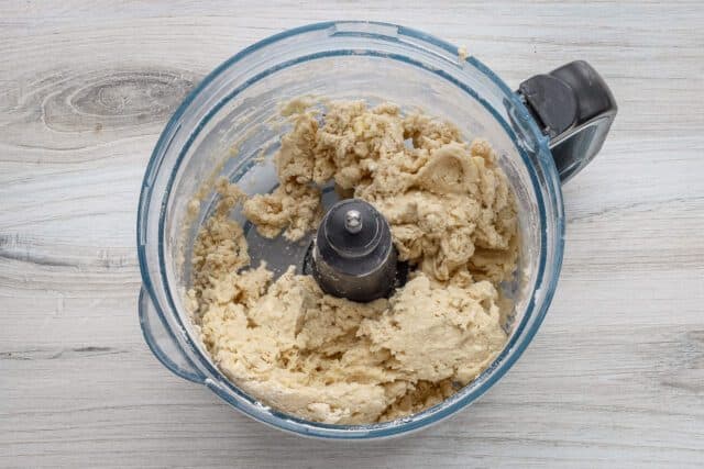 Creamy dough mixture in food processor bowl.