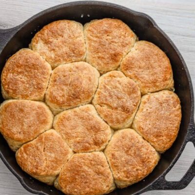Buttermilk biscuits baked to golden brown in a black skillet.