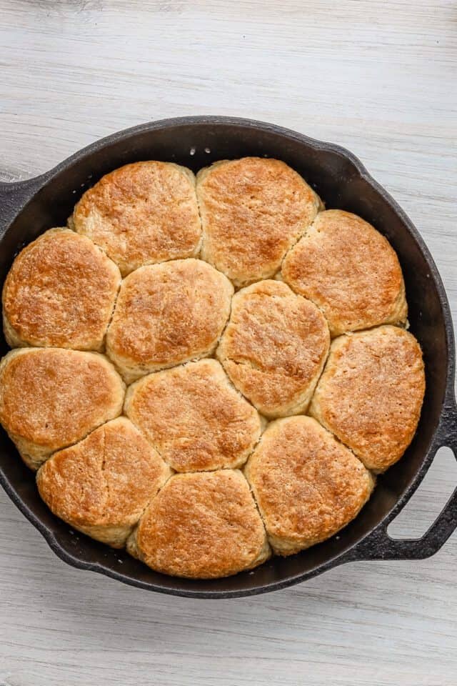 Buttermilk biscuits baked to golden brown in a black skillet.