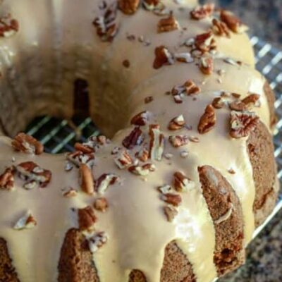 A glazed apple bundt cake on a cooling rack