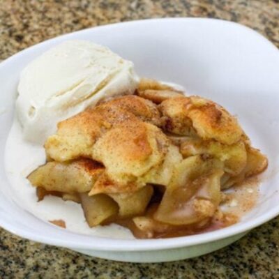 best ever apple cobbler in a serving dish with a scoop of ice cream