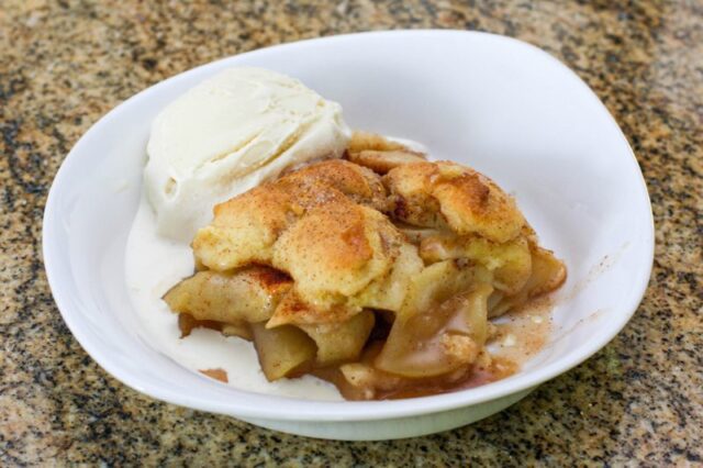 best ever apple cobbler in a serving dish with a scoop of ice cream