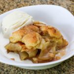 apple cobbler in a serving dish with ice cream on the side.