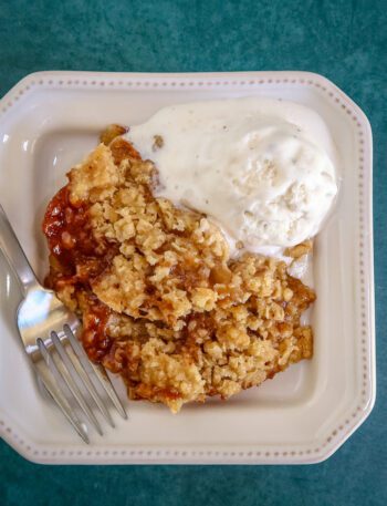 a serving of apple crisp on a plate with ice cream
