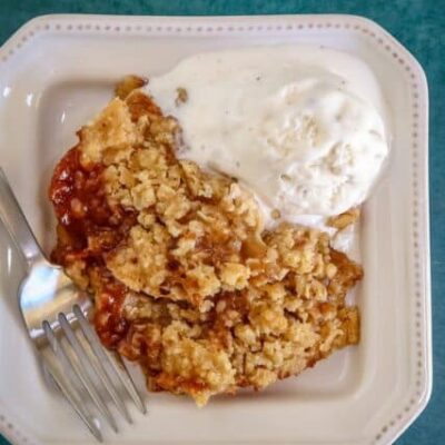 a serving of apple crisp on a plate with ice cream