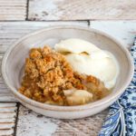 a dish of apple crumble with vanilla ice cream