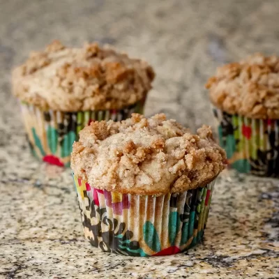 Freshly baked muffins with crumbly tops on a granite countertop.