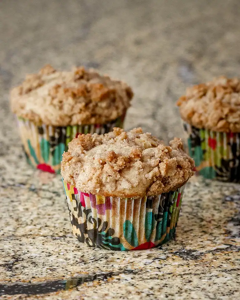 Freshly baked muffins with crumbly tops on a granite countertop.
