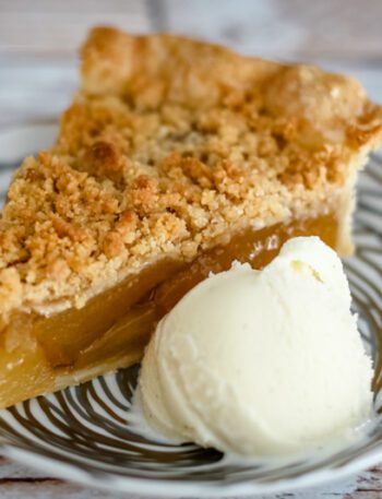 A slice of apple crumble pie with a scoop of ice cream.