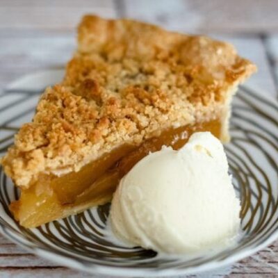 A slice of apple crumble pie with a scoop of ice cream.