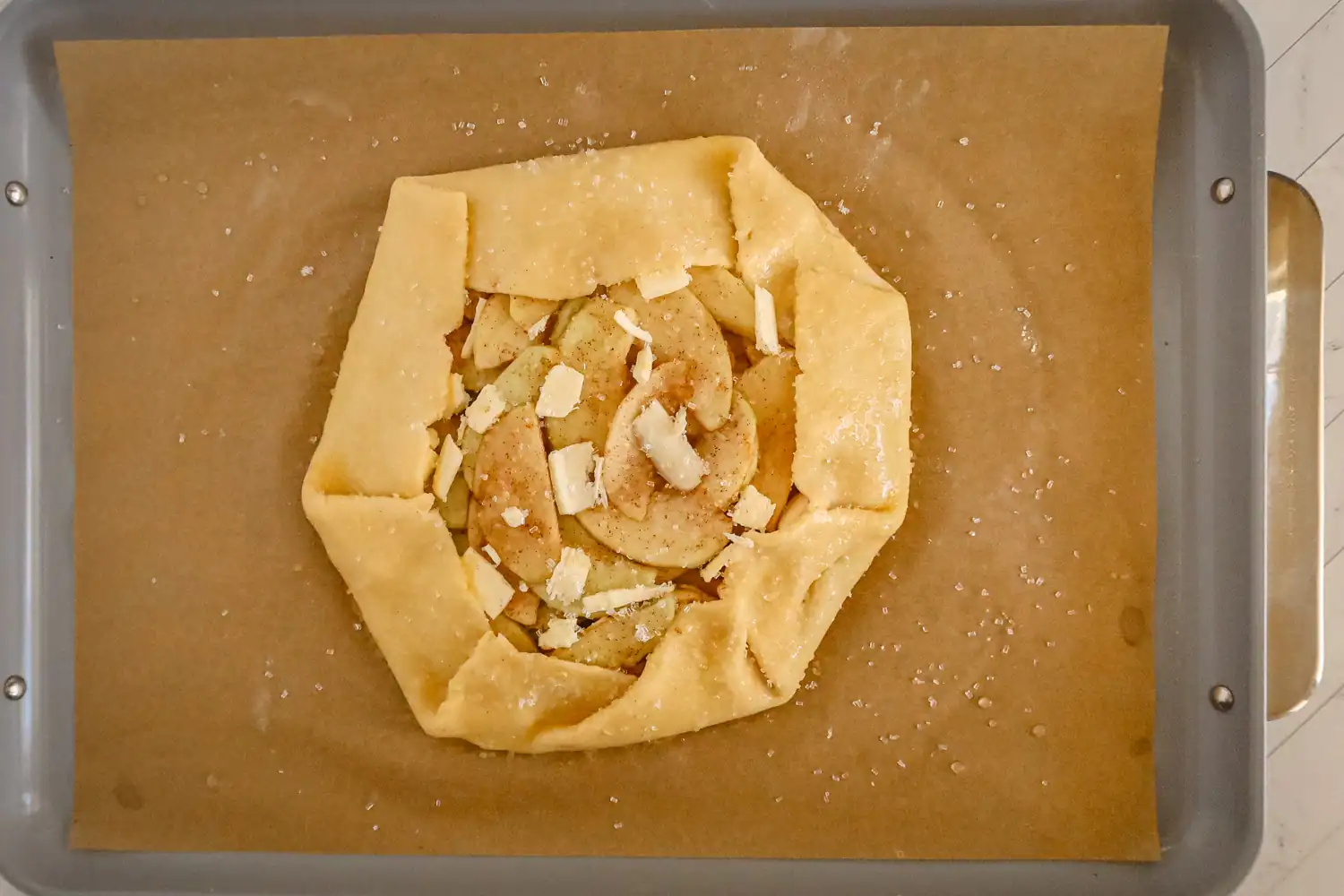 Apple Galette assembly with egg wash, coarse sugar, and butter.