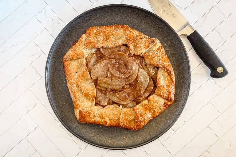 Golden-brown apple galette with a flaky crust in a black skillet.