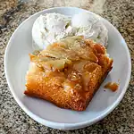 Butterscotch apple crumble with vanilla ice cream on a white dish.
