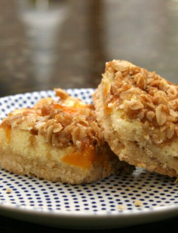 apricot cream cheese bars with shortbread crust and crumb topping, on a plate
