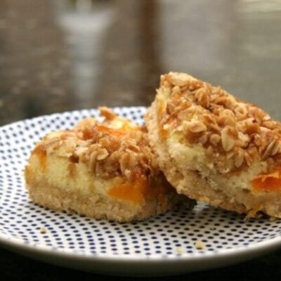 apricot cream cheese bars with shortbread crust and crumb topping, on a plate