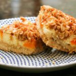 oat crumb-topped apricot cheesecake bars on a dessert plate.