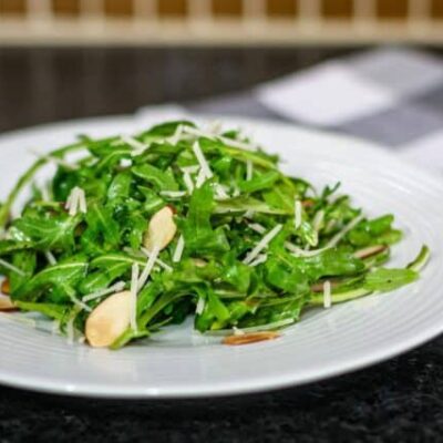 simple arugula salad with sliced almonds on a plate