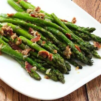 a plate of asparagus with bacon and light mustard sauce for flavor